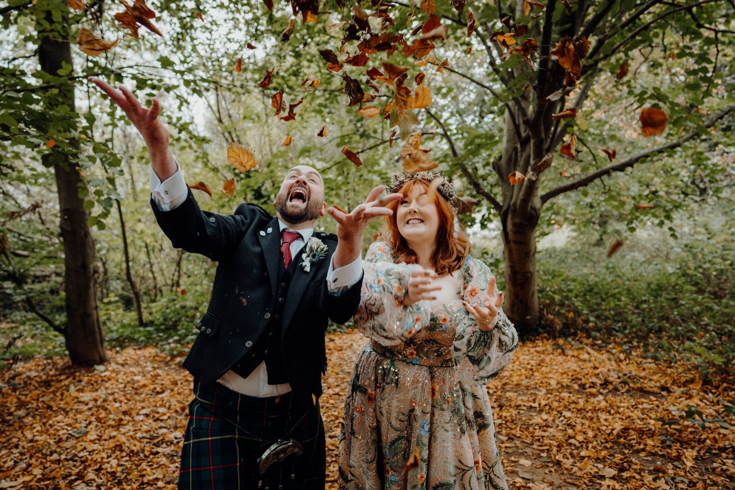Duddingston Loch Wedding // Bride and Groom throw autumnal leaves in the air as confetti / documentary wedding photographer / boda photography